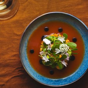 A beautifully plated dish at Burdock & Co. in Vancouver, topped with delicate edible flowers and artistic garnish.